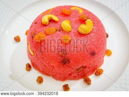 Beautiful, Ready-to-eat Pink Rava Kesari Mound In A White Plate Garnished With Cashew Nuts & Raisins