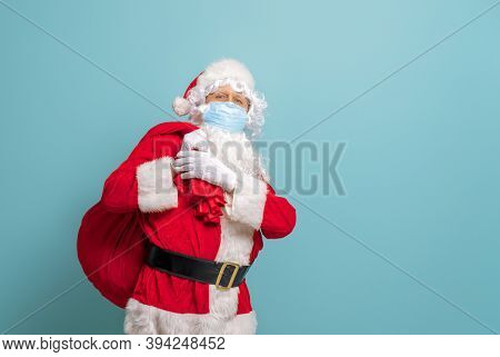 Merry Christmas and Happy Holidays! Santa Claus in face mask on bright color background. Covid-2019
