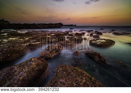 Amazing Seascape For Background. Beach With Rocks And Stones. Low Tide. Motion Water. Clear Sky. Sun
