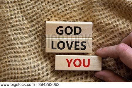 Concept Words 'god Loves You' On Wooden Blocks On A Beautiful Canvas Background, Male Hand. Copy Spa