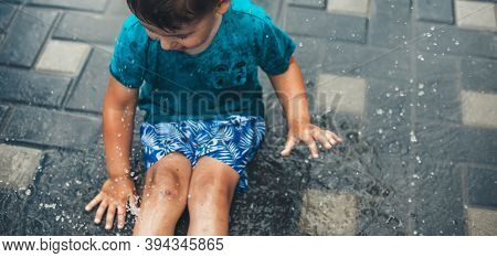 Upper View Photo Of A Caucasian Boy Playing In The Ground In Water Wearing Blue Clothes In The Backy