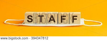 Staff The Word Is Written On Wooden Cubes Lying On A Medical Mask. Concept. Yellow Background