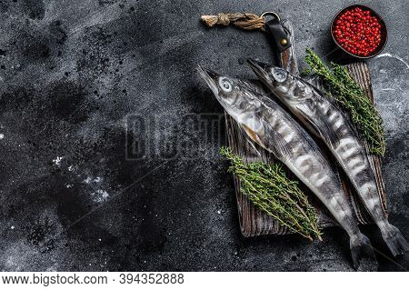 Raw Icefish On A Wooden Cutting Board. Black Background. Top View. Copy Space.