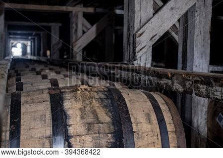 Long Lines Of Bourbon Barrels In Racks Aging Warehouse