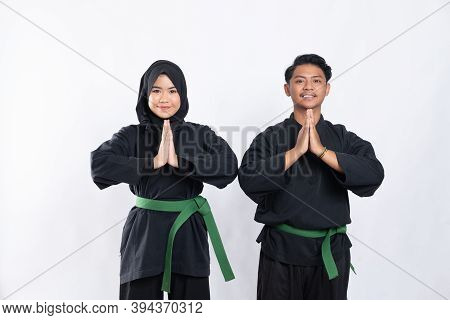 Hooded Women And Men In Pencak Silat Uniform Poses Respectfully With Both Hands Cupped In Front Of C