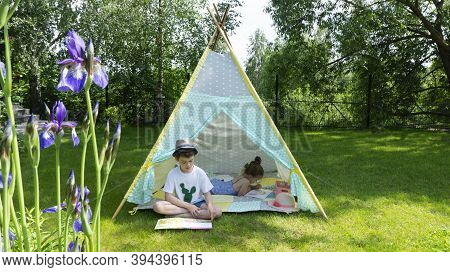 Girl Draws With Crayons In A Tipi Patchwork During The Summer Holidays. A Schoolboy Recently Learned