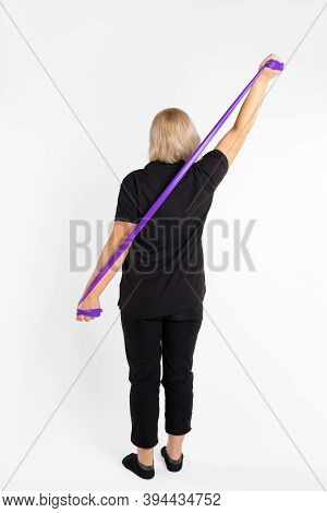 Photo Of Senior Woman From The Back, Whipping With An Elastic Band Straightens Her Posture. On A Whi