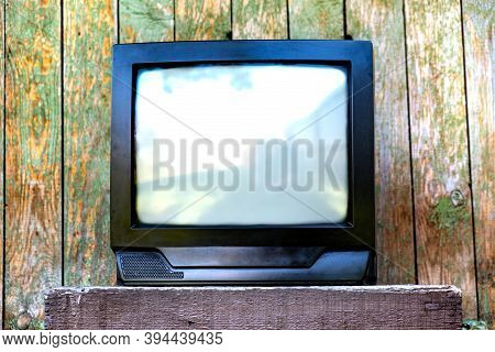 Old Analog Television Set On The Weathered Wooden Planks Background