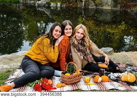 Three Women Best Friends At Autumn Picnic In The Park. Colorful Plaid, Thermos And Pumpins. Friends 