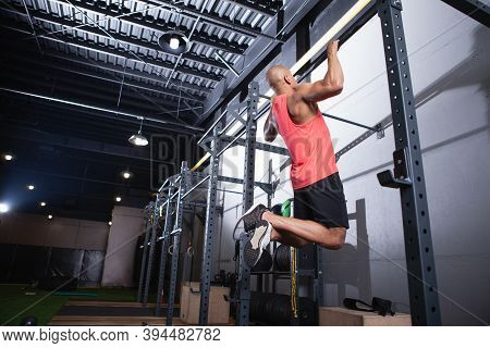 Low Angle Rear View Shot Of A Muscular African Male Athlete Doing Pull Ups At The Gym, Copy Space. S