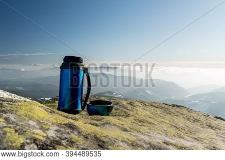 Thermos For Drinks On A Background Of Mountains. Thermos On A Stone Outdoors.