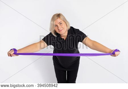 Sporty Senior Woman On A White Background Stretches Out A Fitness Elastic Band In Her Hands And Bend