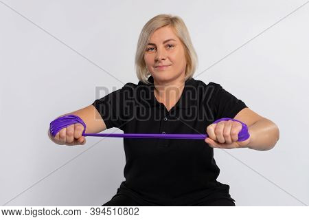 Portrait Of A Senior Woman Stretching A Fitness Elastic Band In Front Of Her. Photo On A White Backg