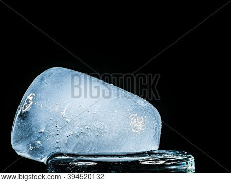 Ice Melts And Rotates On A Black Background. Extreme Close Up. Crystal Ice Cube With Frozen Water Th