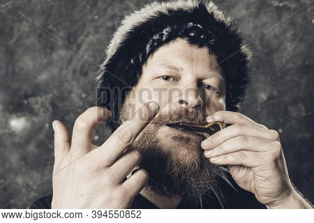 Matured Man In Fur Hat Playing Jews Harp