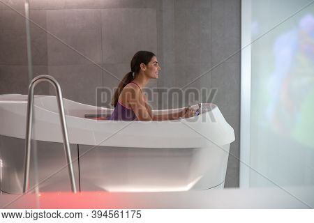 Dark-haired Female Sitting In Hydromassage Bathtub, Enjoying Hydromassage