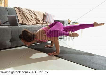 Balanced. Beautiful Young Woman Working Out Indoors, Doing Yoga Exercise On Gray Mat At Home. Unreco