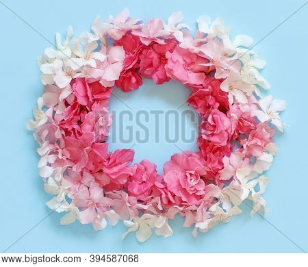 Frame Of Pink Flowers Over A Light Blue Background Top View