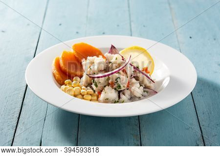 Traditional Peruvian Ceviche With Fish, Sweet Potato, Corn And Vegetables On Blue Wooden Table
