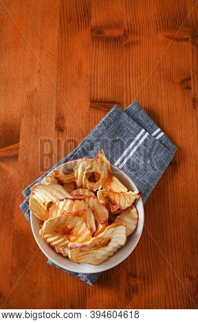 Bowl of dried apple slices - apple chips or rings - on gray napkin