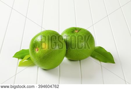 Two whole sweetie fruits (green grapefruits, pomelits) and leaves