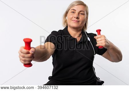 Senior Woman Doing Sports At Home With Dumbbells Listen To The Music With Headphones. Fitness Concep