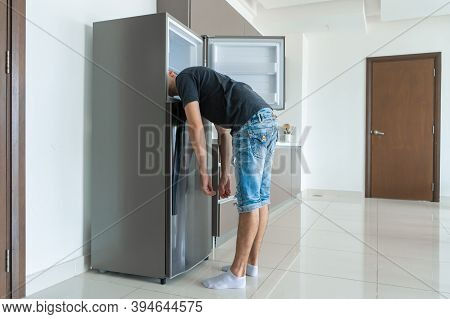 On A Hot Day, The Guy Cools With His Head In The Refrigerator. Broken Air Conditioner.