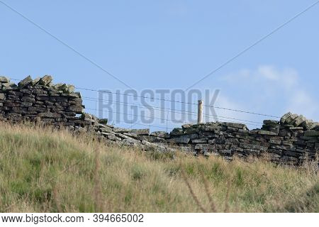 Profile Of Drystone Wall And Barbed Wire Fence Against Pastel Blue Sky Background. Autumn Rural Seas
