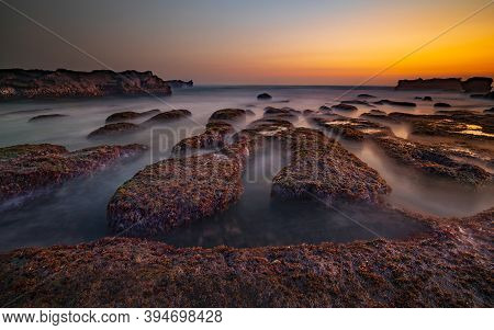 Amazing Seascape For Background. Beach With Rocks And Stones. Low Tide. Motion Water. Clear Sky. Sun