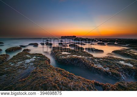 Amazing Seascape For Background. Beach With Rocks And Stones. Low Tide. Motion Water. Clear Sky. Sun