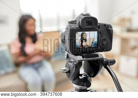 blogging, videoblog and people concept - happy smiling african american female video blogger with parcel box and camera videoblogging at home