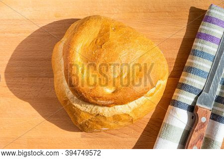 A Loaf Of Homemade Wheat Bread On A Wooden Board, A Rustic Striped Kitchen Towel And A Knife With A 