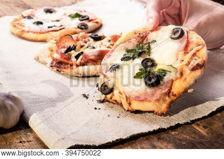 Traditional Italian Appetizer - A Woman Takes A Mini Pizza, Pizzetta With Sausage, Olives And Mozzar