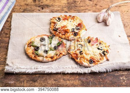 Several Ready-made Mini Pizza, Pizzetta On A Linen Napkin On A Wooden Table