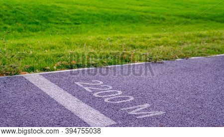 Jogging Track In The Park At Summer Day. 2000 Meters Distance Sign Painted On Asphalt Pavement. Jogg