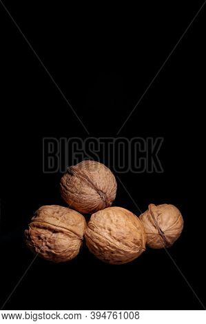 Four Walnuts Isolated On Black Background, Side View, Vertical Photo, Flatlay, Screen Saver On The P