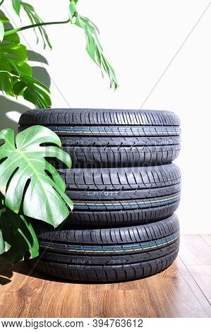 New Summer Tires Against The Backdrop Of A Beautiful Monster Flower And A White Wall Lie On A Wooden