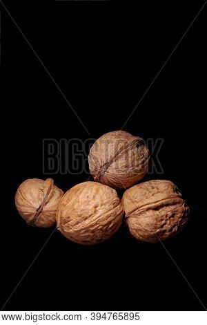 Four Walnuts Isolated On Black Background, Side View, Vertical Photo, Flatlay, Screen Saver On The P
