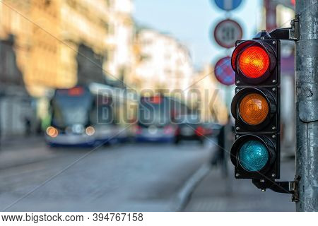 Close-up Of Small Traffic Semaphore With Red Light Against The Backdro Of The City Traffic