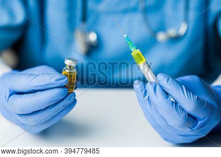 Coronavirus COVID-19 vaccine development,research for cure & treatment of infected patients,groundbreaking discovery in battle against SARS-CoV-2 pathogen,hands in gloves holding ampoule & syringe jab