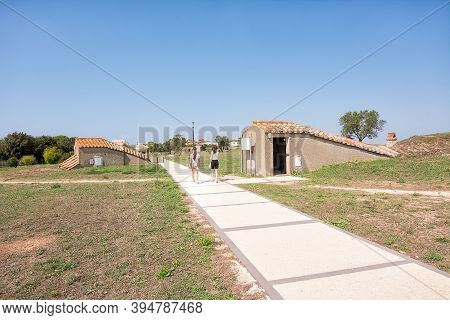 Tarquinia, Italy - 18 September 2020: Pedestrian Path With Tourists Between The Entrances To The Tom
