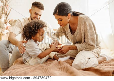 Happy Family Multi Ethnic Mother Feels Sorry For Baby Who Hurt The Leg In Bed In Bedroom At Home