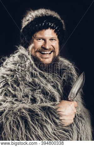 Bearded Hunter Dressed In A Fur Mantle And Fur Hat With Knife