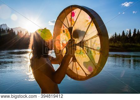 A Creative Back Lit Into The Sun Shot With Lens Flare, Of A Spiritual Guy Playing Traditional Native