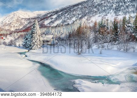 Astonishing Winter Scenery With Frozen River With Wooden Houses And Snow Covered Pine Trees Near Val