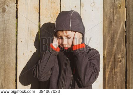 A Teenage European Boy In A Hood Covered His Ears With His Hands. The Child Doesn't Want To Listen.