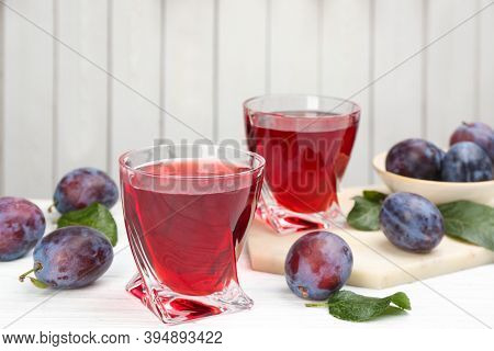 Delicious Plum Liquor And Ripe Fruits On Table Against White Background. Homemade Strong Alcoholic B
