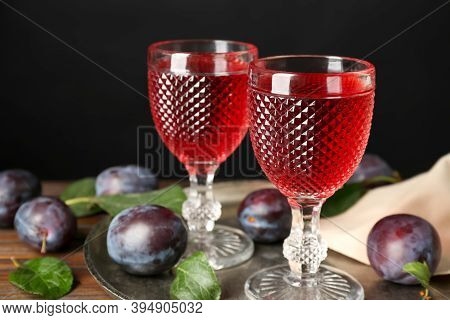 Delicious Plum Liquor And Ripe Fruits On Wooden Table Against Black Background. Homemade Strong Alco