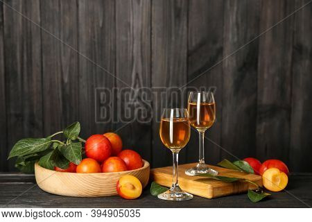 Delicious Plum Liquor And Ripe Fruits On Black Wooden Table. Homemade Strong Alcoholic Beverage