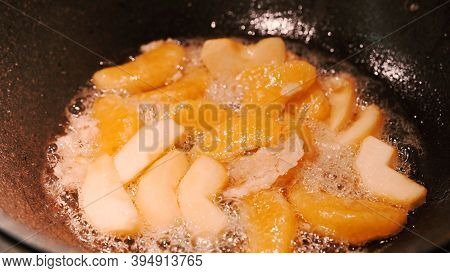 Apple And Orange Are Fried In A Pan In A Sugar Sauce